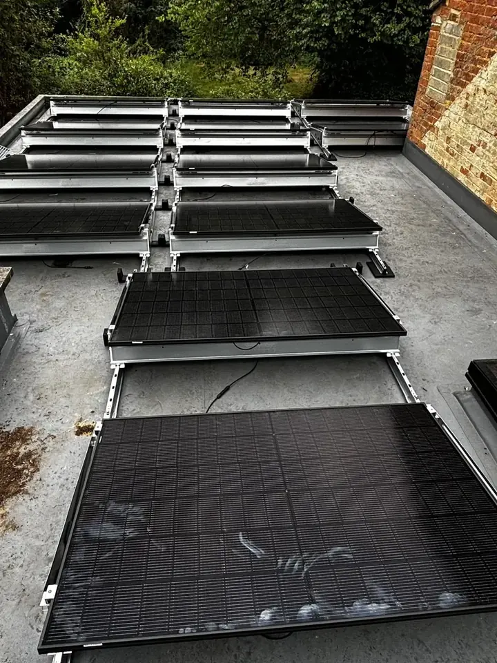 Black Canadian Solar panels raised on frames across a flat roof in Tadley