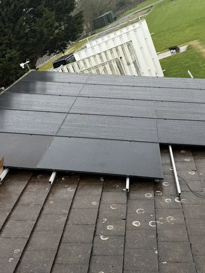 Black solar panels being laid out across the roof during installation